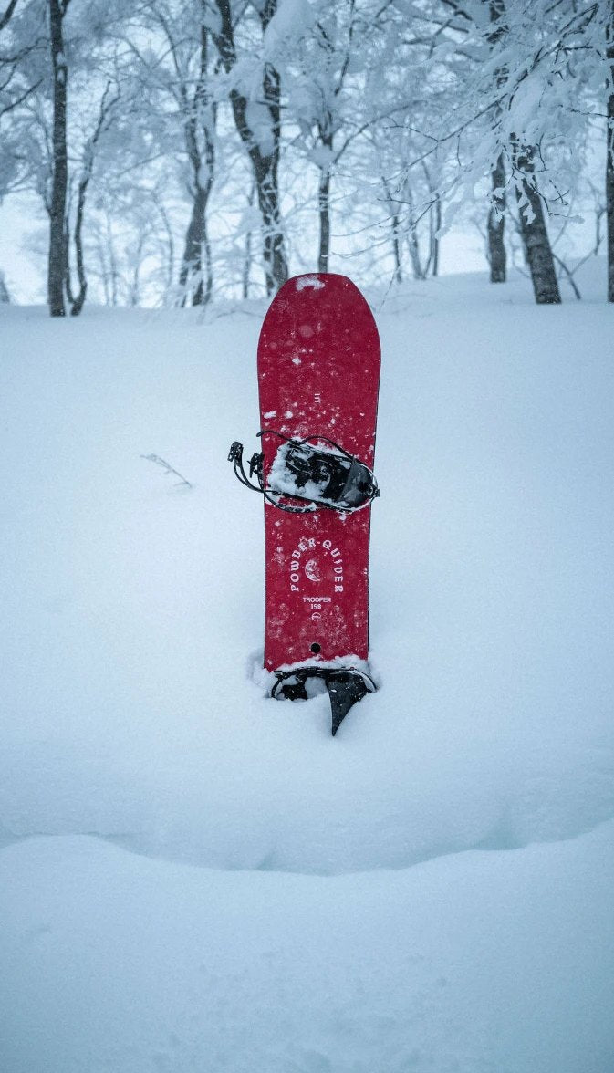 Endeavor Trooper Pro snowboard standing in deep powder among snow-covered trees