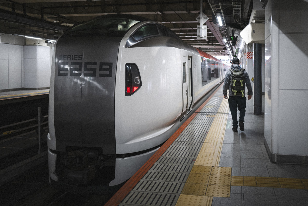 Rider wearing the Endeavor Mountain Pack in Moss on a train platform