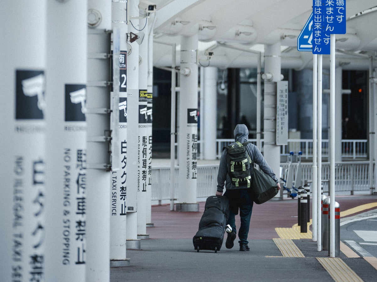 Rider rolling the Endeavor Utility Snowboard Bag along an airport kerb in Japan