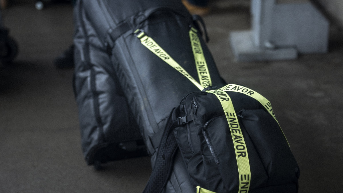 Endeavor Utility Snowboard Bag loaded with a Mountain Pack under its cargo straps, rolling through an airport