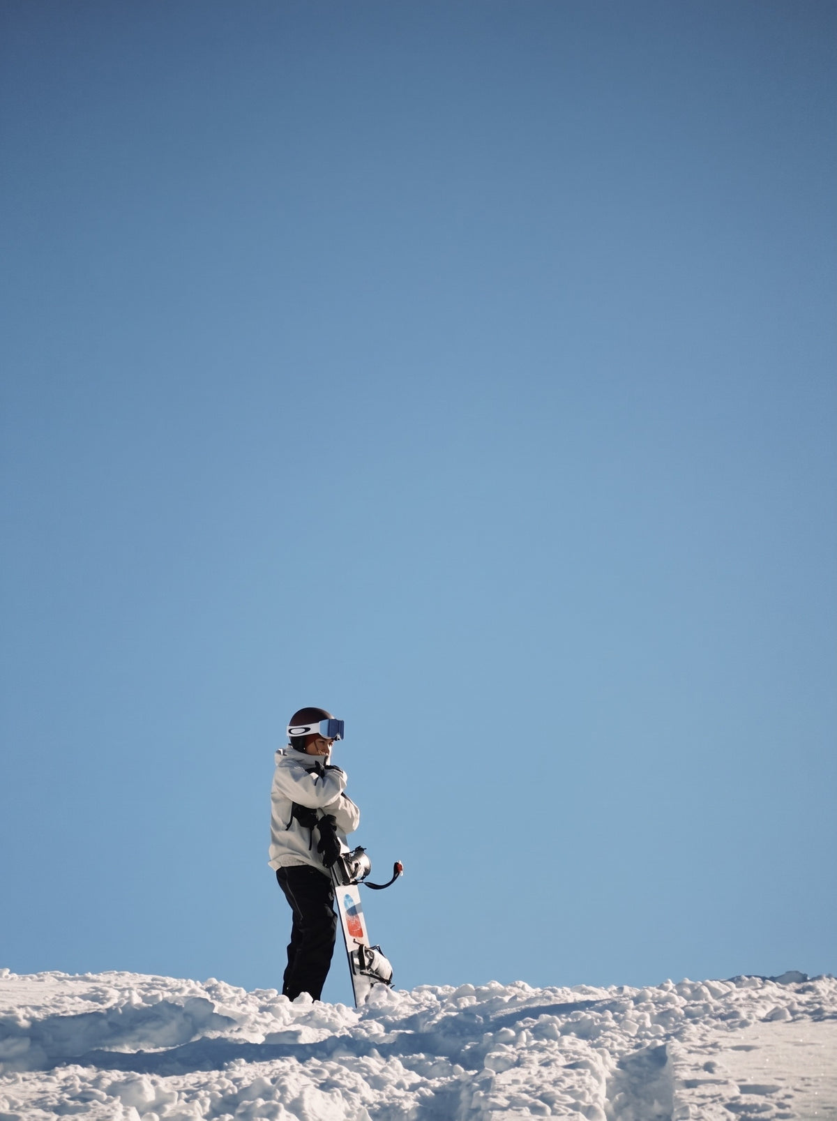 Rider on a snowy ridge under a clear blue sky with her B.O.D. Womens