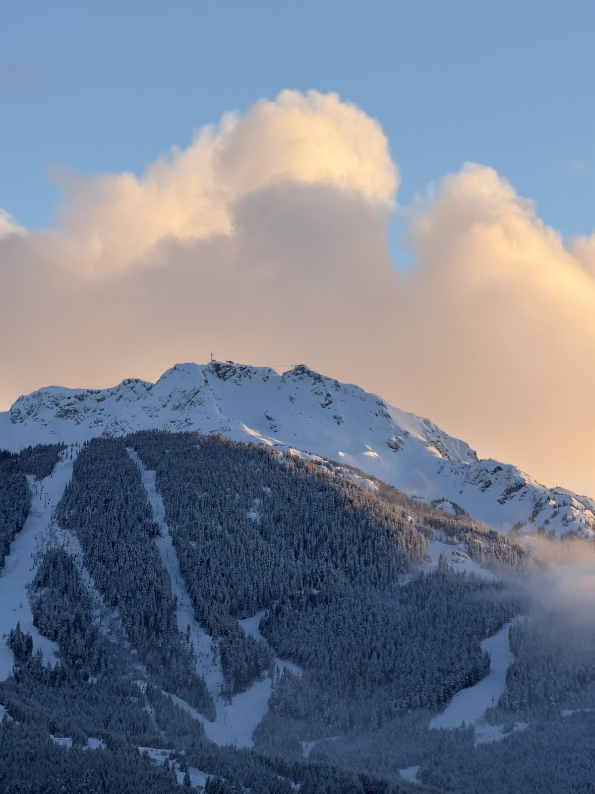 Snow-covered mountain peak under clouds at sunset