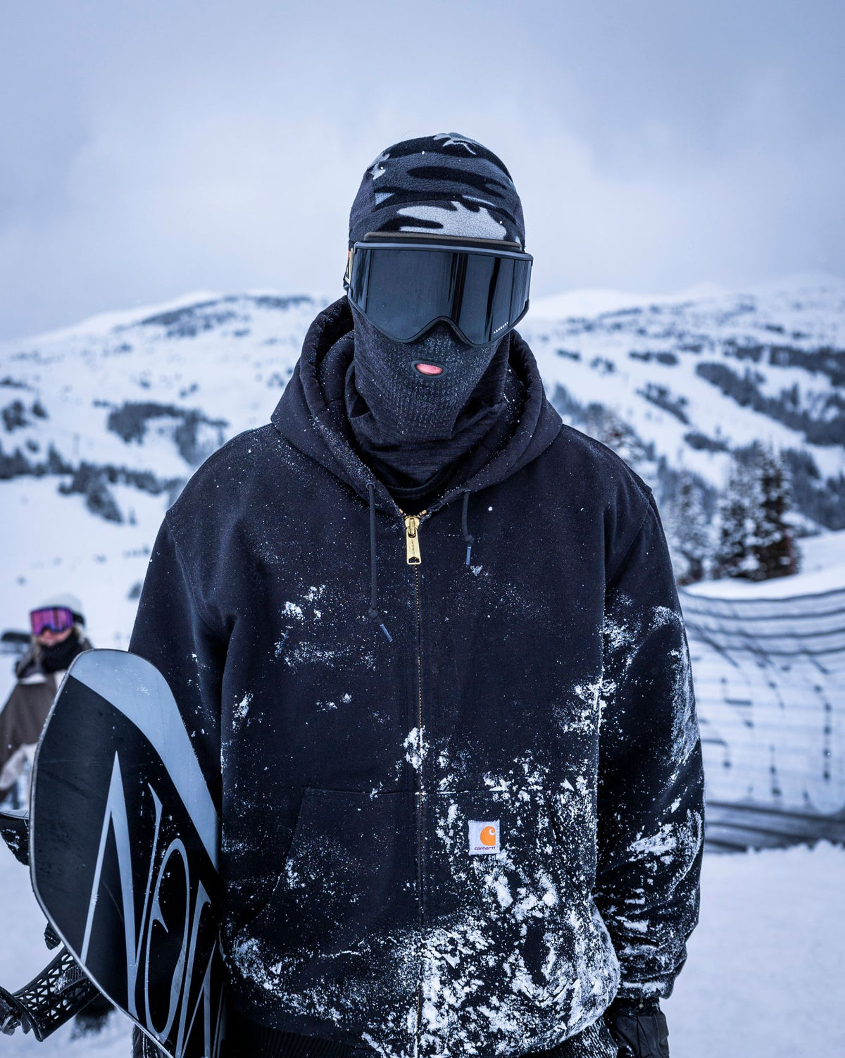 Rider in an Airhole balaclava with the Breath Hole, snowboard in hand, on the mountain