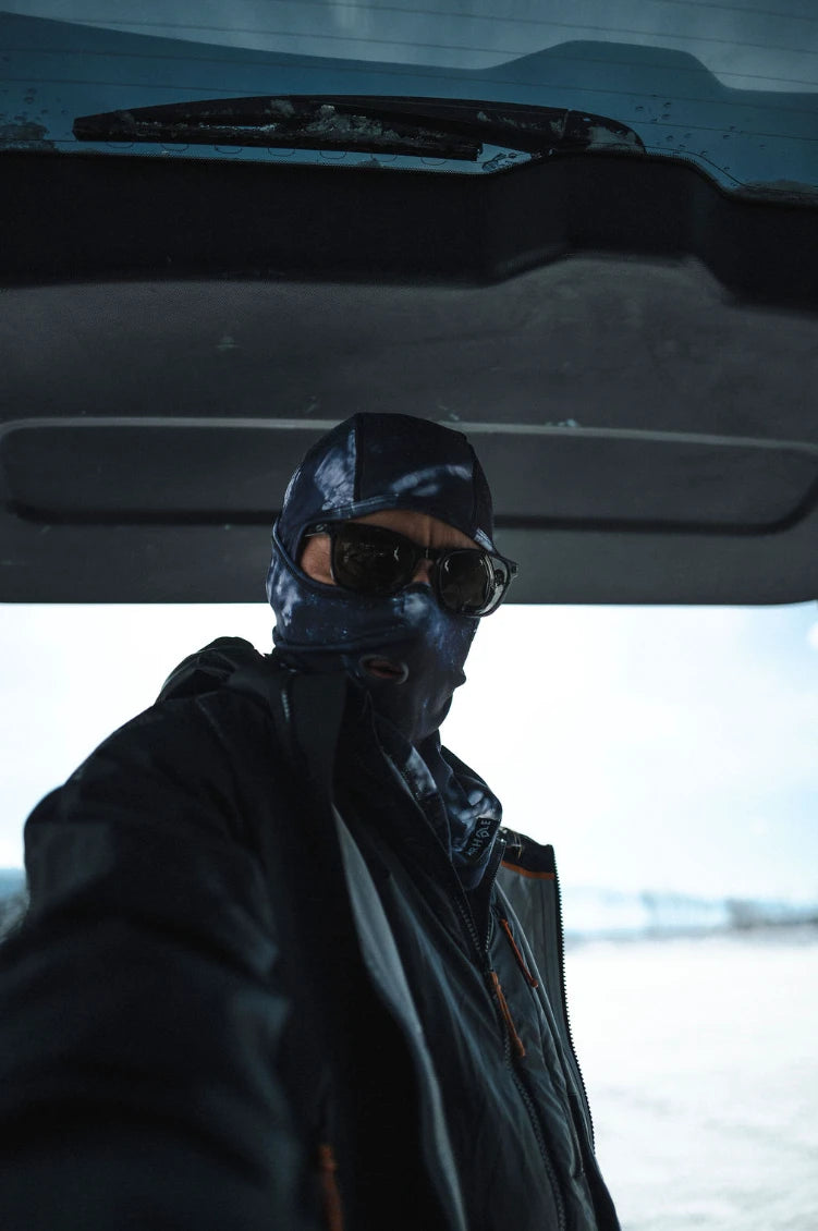 Rider in a printed Airhole balaclava and sunglasses under a car's open tailgate