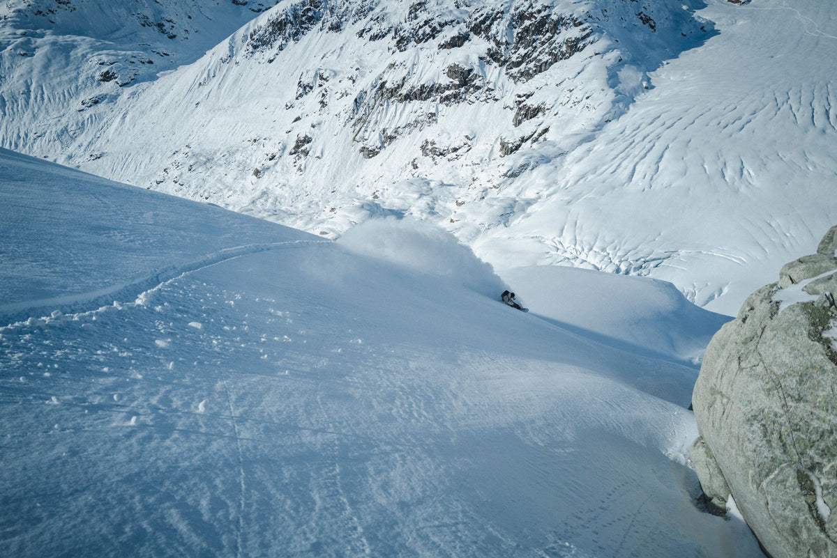 Snowboarder carving a powder turn above a glacier