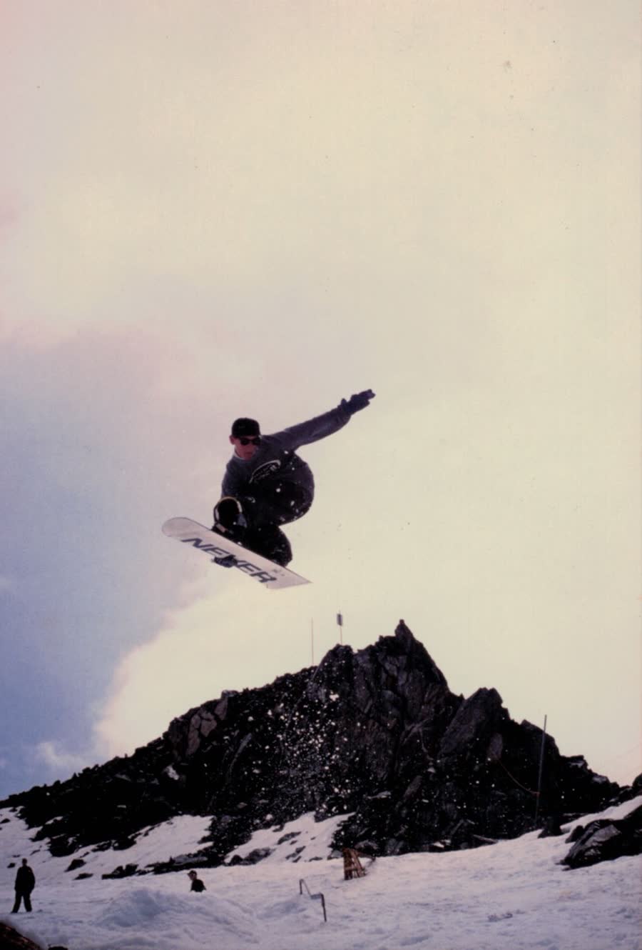 Snowboarder in the air above a rocky peak